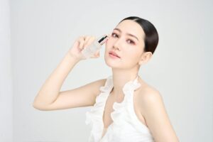 Serene model holding skincare product in modern beauty photoshoot.